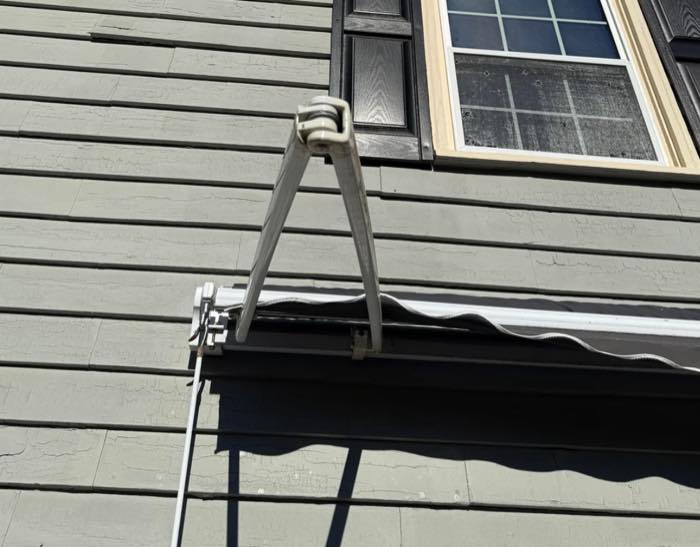 One folding arm remaining open while a retractable awning is being retracted